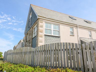 Exterior view of a two story house with a wooden fence and plants in front at Henrys Croft in Lizard