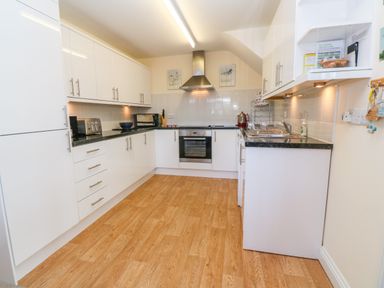 A kitchen with white cabinets wooden floor and stainless steel appliances at Henrys Croft in Lizard