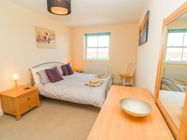 A bedroom with a double bed bedside tables a chair a dresser with a bowl and a window at Henrys Croft in Lizard