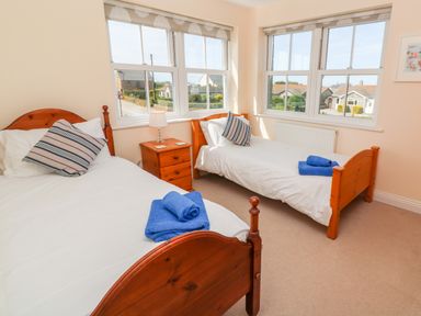 A bedroom with two single wooden beds and a wooden bedside table with a lamp at Henrys Croft in Lizard