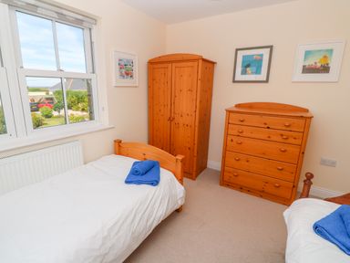 A bedroom with two single beds wooden wardrobe and chest of drawers at Henrys Croft in Lizard