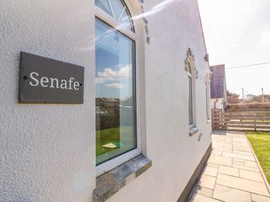 A white building exterior with windows and a black sign that reads Senafe at Senafe in Widemouth Bay