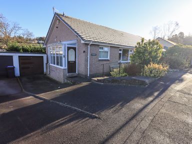 A bungalow with a driveway and garage surrounded by bushes at Fairfell in Keswick
