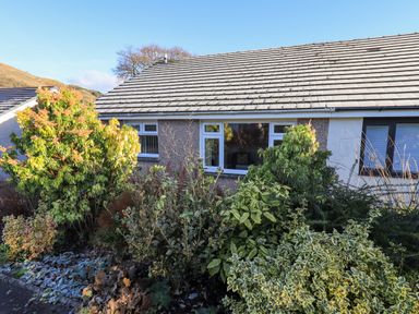 Front view of a single story house with windows and bushes in the garden at Fairfell in Keswick