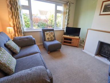 A sitting room with a sofa armchair television and fireplace at Fairfell in Keswick
