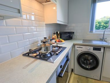 A kitchen countertop with two pots on a gas stove and a washing machine under the counter at Fairfell in Keswick