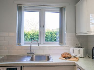 A kitchen counter with a sink loaf of bread a knife and a toaster under a window at Fairfell in Keswick