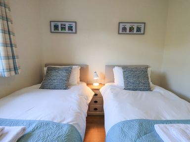 A bedroom with two single beds separated by a wooden nightstand with a lamp at Fairfell in Keswick