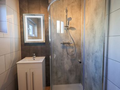 A bathroom with a shower enclosure a sink vanity unit and a mirror at Fairfell in Keswick