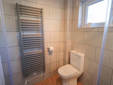 A bathroom with a toilet a wall-mounted radiator and a window at Fairfell in Keswick