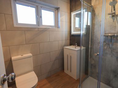 A bathroom with a toilet sink with cabinet and a glass shower enclosure at Fairfell in Keswick