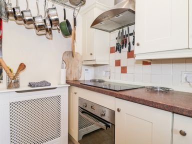 A kitchen with hanging pots and pans a stove an oven and knives on a magnetic strip at Combe Cottage Brimscombe near Stroud