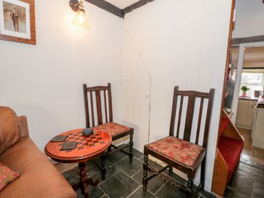 A sitting area with two wooden chairs and a round table beside a brown sofa at Combe Cottage Brimscombe near Stroud
