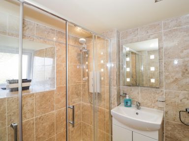 A bathroom with a glass shower enclosure sink with cabinet and a mirror at Combe Cottage Brimscombe near Stroud