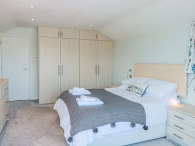 A bedroom with a bed towels on a knitted blanket a wardrobe and a chest of drawers at Estuary View House and Annexe Dartmouth