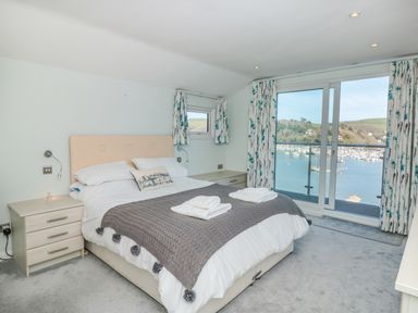 A bedroom with a bed two nightstands and sliding glass doors overlooking a harbor at Estuary View House Annexe in Dartmouth