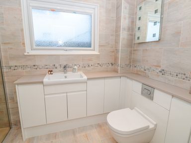 A bathroom with a sink and toilet and cabinets under a frosted window at Estuary View House and Annexe in Dartmouth