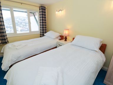A bedroom with two single beds and a window with curtains at Estuary View House Annexe in Dartmouth