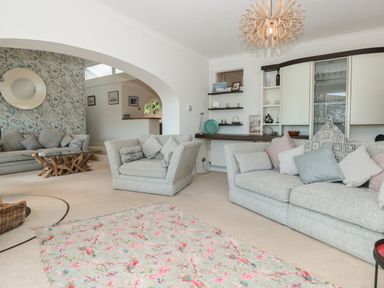 A living room with sofas a floral rug and a glass coffee table at Estuary View House and Annexe in Dartmouth