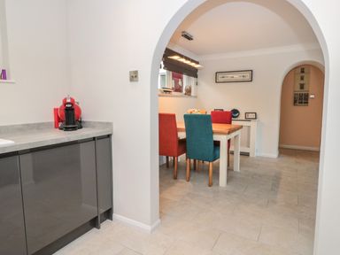 A dining area with a wooden table and four chairs in red and blue colors at Estuary View House Annexe in Dartmouth