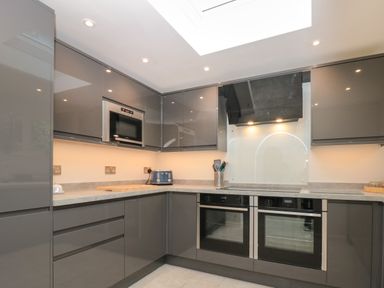 A kitchen with grey cabinets double ovens a microwave and a toaster at Estuary View House and Annexe Dartmouth