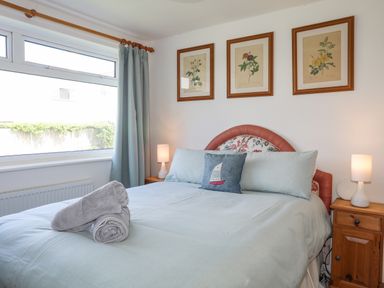 A bedroom with a bed linens pillows bedside tables and lamps at Crows Nest - Rhosneigr in Rhosneigr