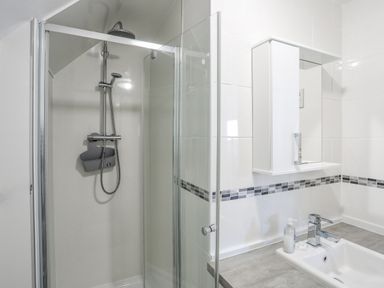 A bathroom with a shower enclosure and a sink with a mirror cabinet above at Crows Nest - Rhosneigr in Rhosneigr