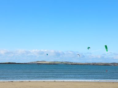 A beach with sand and sea with kite surfers on the water at Crows Nest - Rhosneigr in Rhosneigr