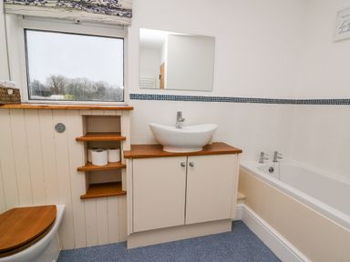 A bathroom with a bathtub sink cabinet toilet with wooden seat and a window at Gwynfa Capel Iwan near Newcastle Emlyn