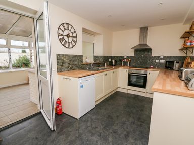 A kitchen with wooden countertops a dishwasher an oven a stove and an open door leading to a tiled room at Gwynfa in Capel Iwan near Newcastle Emlyn