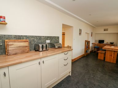 A kitchen with countertop toaster bread box table chairs and shelves at Gwynfa in Capel Iwan near Newcastle Emlyn