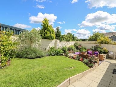 A garden with grass a flower bed and outdoor seating at Gwynfa in Capel Iwan near Newcastle Emlyn