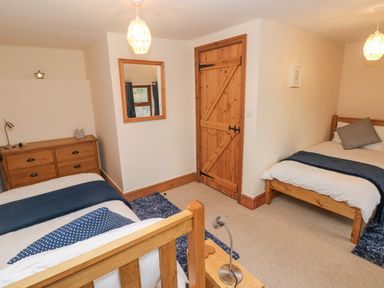 A bedroom with two wooden beds a wooden dresser a wooden door and a wall mirror at Gwynfa in Capel Iwan near Newcastle Emlyn