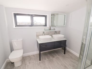 A bathroom with a toilet a double sink vanity and a mirror at Phoenix House in Castlemorton