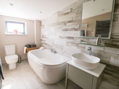 A bathroom with a bathtub toilet sink and mirror at Phoenix House in Castlemorton