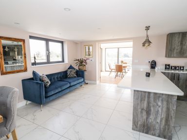 A kitchen and living area with a blue sofa and wooden island at Phoenix House in Castlemorton