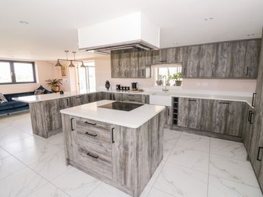 A kitchen with wooden cabinets white countertops and a central island at Phoenix House in Castlemorton