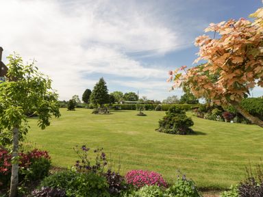 A garden with green lawn and various trees and flowers at Phoenix House in Castlemorton
