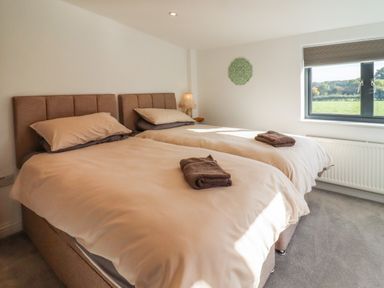 A bedroom with two single beds a window and a lamp at Phoenix House in Castlemorton