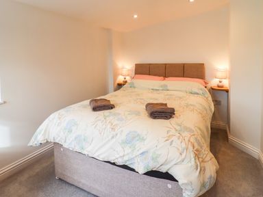 A bedroom with a double bed two bedside lamps and towels on the bed at Phoenix House in Castlemorton