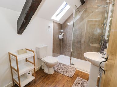 A bathroom with a toilet sink shower unit storage shelf and skylight at Stabla in Chwilog