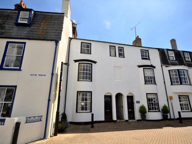 A row of white terraced houses with black framed windows and doors on a paved street at The Ferryman in Weymouth
