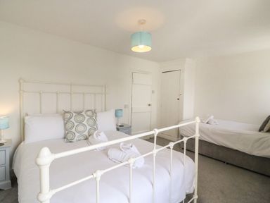 A bedroom with a double bed and a single bed with bedside tables and lamps at The Ferryman in Weymouth