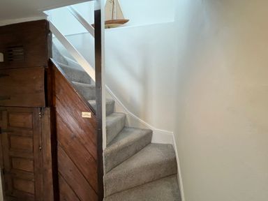A carpeted staircase with white railing and wooden paneling on the side at The Ferryman in Weymouth