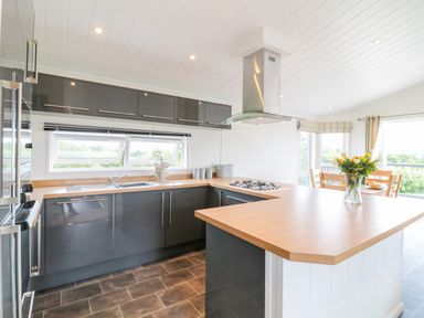 A kitchen with black cabinets a wooden countertop and a vase of flowers on the counter at Alder Lodge in Teigngrace near Newton Abbot