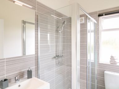 A bathroom with a sink, shower, toilet, and window at Alder Lodge in Teigngrace near Newton Abbot