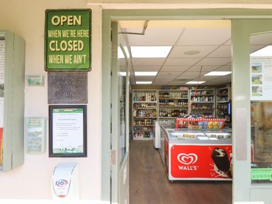 A small shop interior with shelves stocked with food and drink items and an ice cream freezer at Birch Lodge in Teigngrace near Newton Abbot