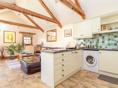 A kitchen and living area with wooden beams leather sofas and tiled floor at Valley View in St Martin near Mawgan