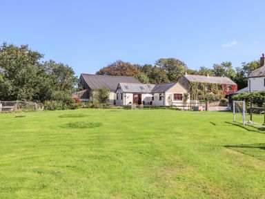 A large green lawn with soccer goalposts and houses in the background at Valley View in St Martin near Mawgan