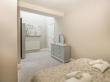 A bedroom with a bed with folded towels and a dresser with a mirror at Harbour Watch 2 in Weymouth